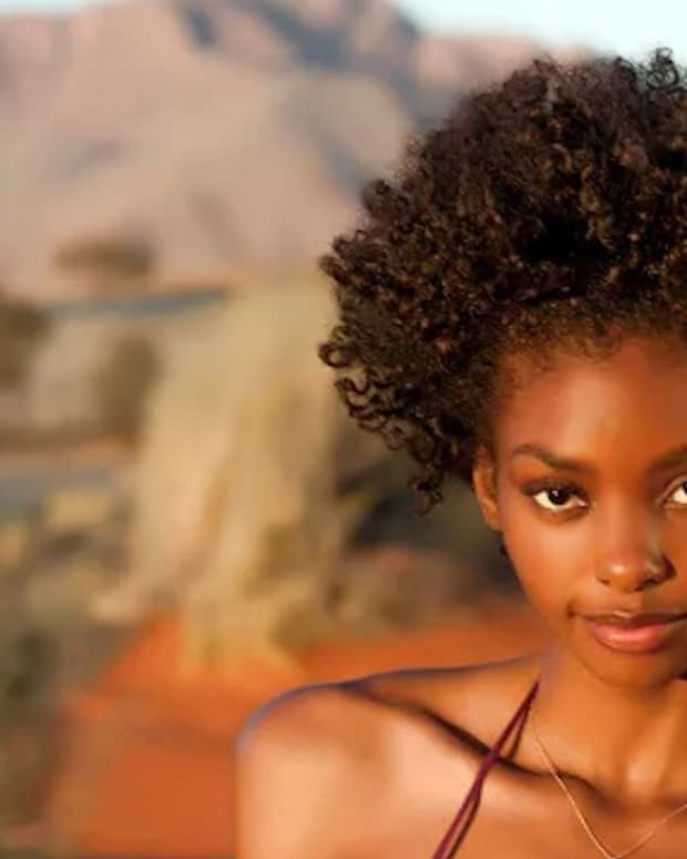 Adaora poses in a pink bikini in front of the scenic mountains and high grass of Namibia.